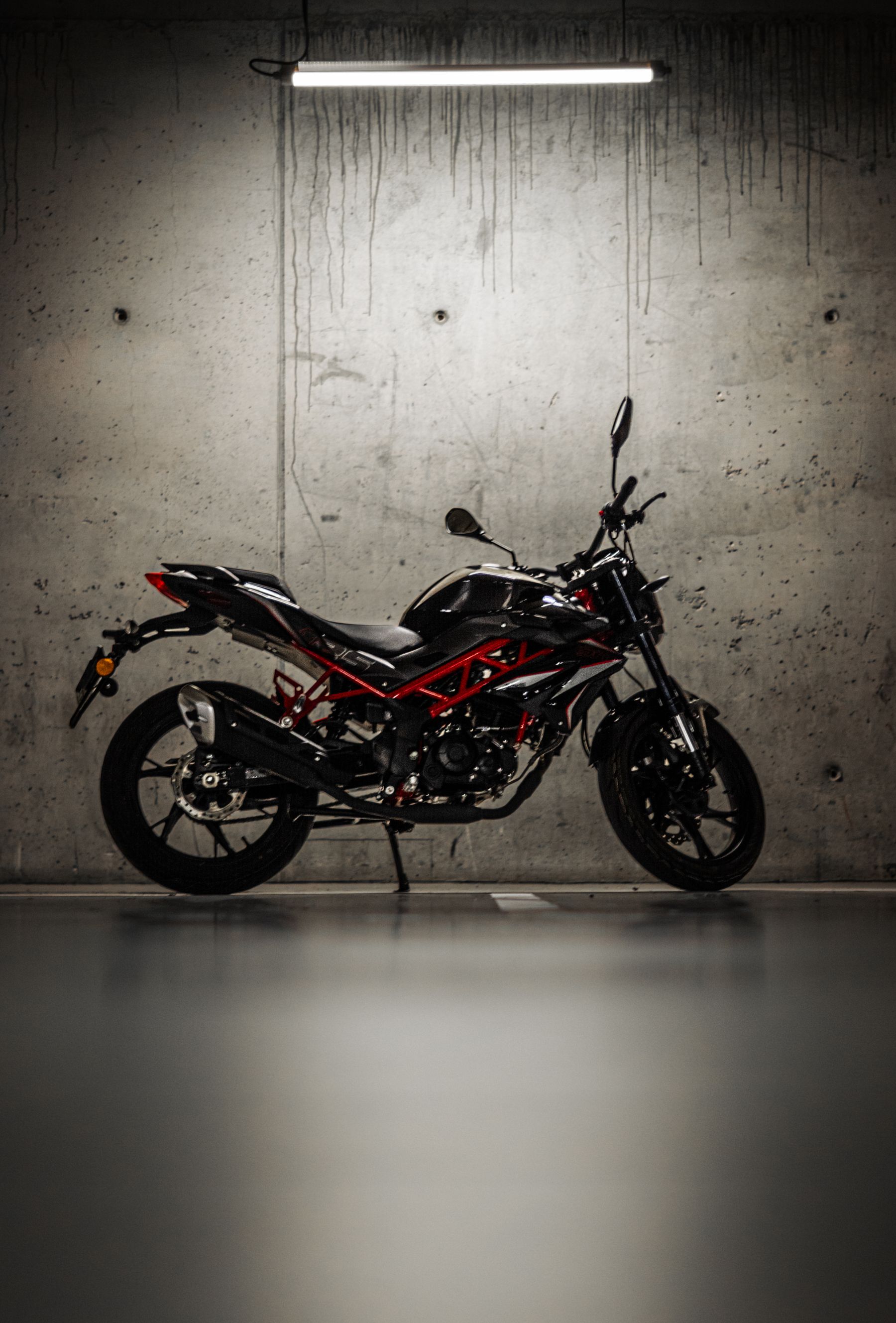 Black and red Benelli naked motorcycle under a garage light